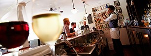 Closeup of glasses of red and white wine with people talking in the background.