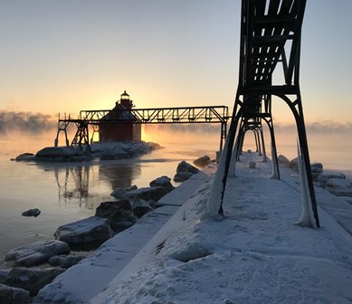 A red lighthouse at the end of a snow outcropping