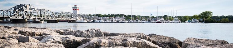 Distance shot over the water looking at a bridge, marina and rocks.