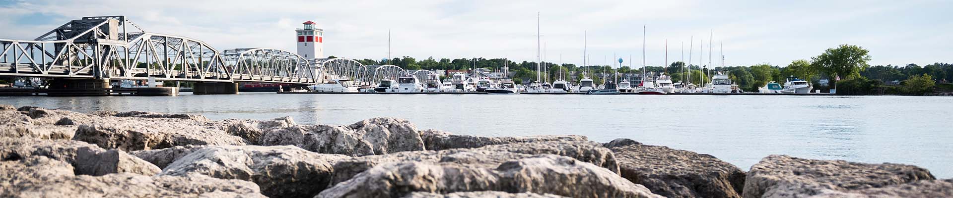 Distance shot over the water looking at a bridge, marina and rocks.