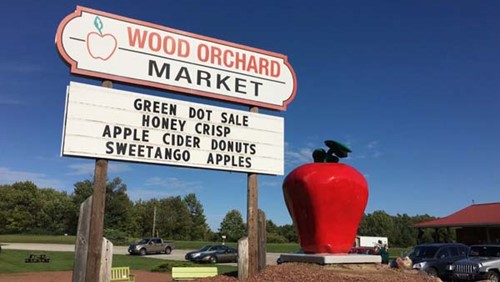 The Wood Orchard sign featuing honey crisp apples, apple cider, donuts, and sweetango apples.