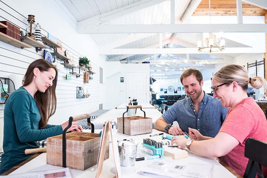 Three people sitting at a table making crafts together