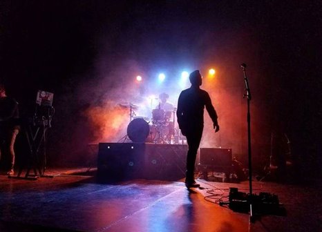 Silhouette of a band on stage backlit by colored lights.