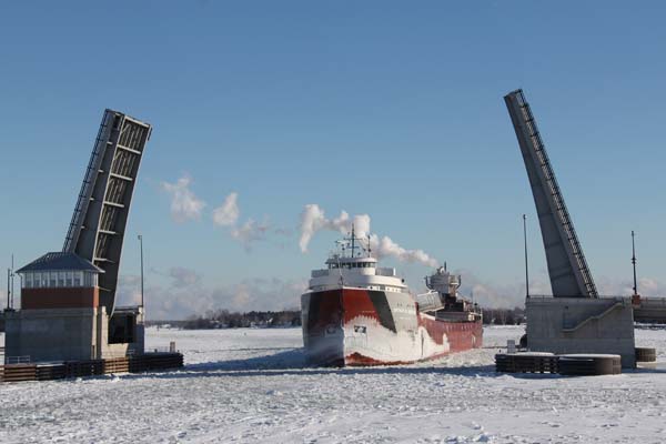 A winter freighter moves through the ice, heading toward land.