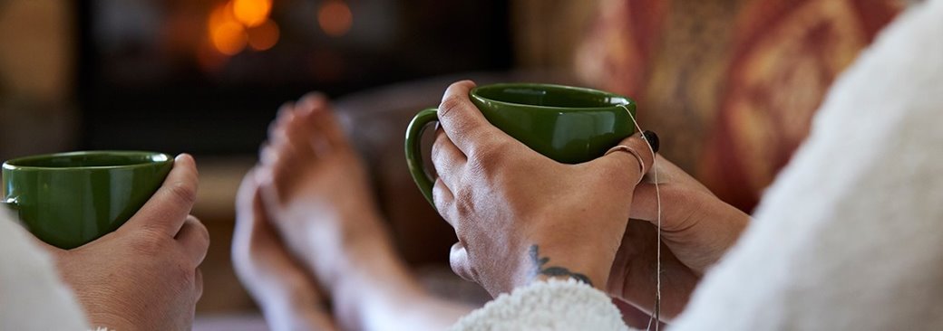 Closeup of people in robes with their feet up drinking tea.