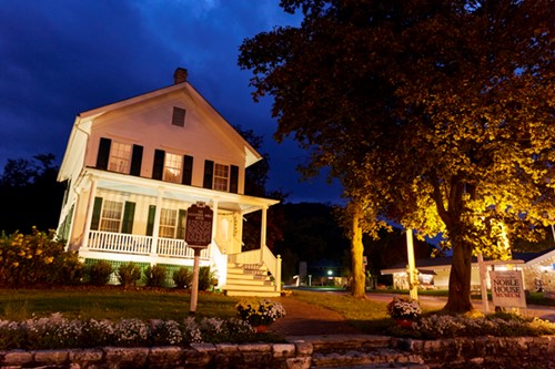 The exterior of Noble House lit up at night.