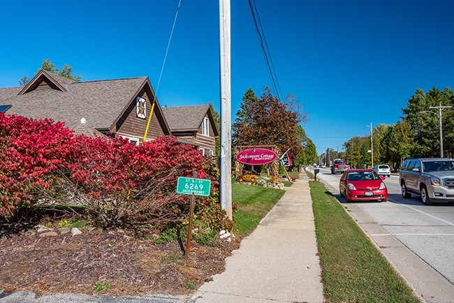 Sidewalk near buildings and cars driving down a street.