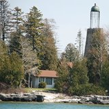 An old lighthouse surrounded by trees at the lakeshore.