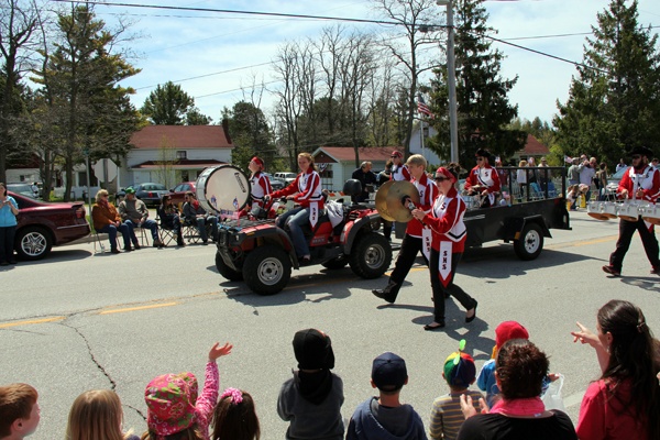 A parade going down a street with people watching