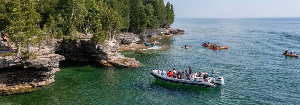 A motor boat pulling up to a cliff line.