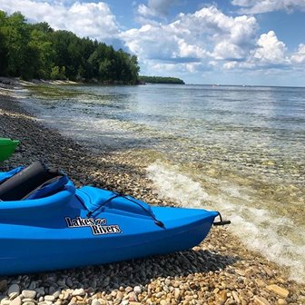 A kayak parked on a pebble and stone beach