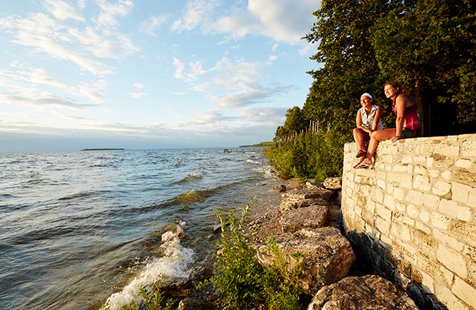 Two women sitting on a wall near the lake