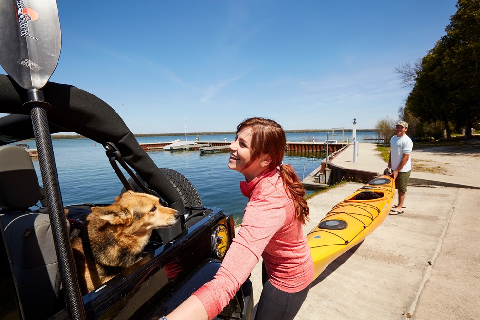 A man and woman with a dog getting a kayak ready.