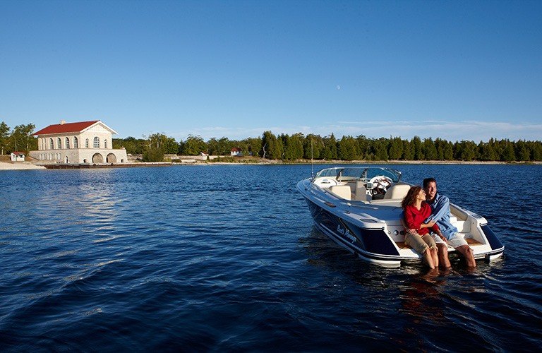 A couple on the back of a boat near Rock Island with the boat house in the background