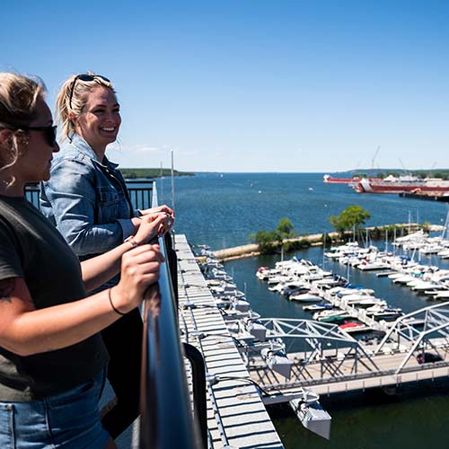 Women on a bridge overlooking a marina