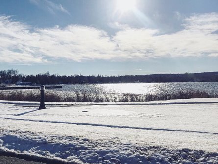 Sun shining over the lake with snow in the foreground