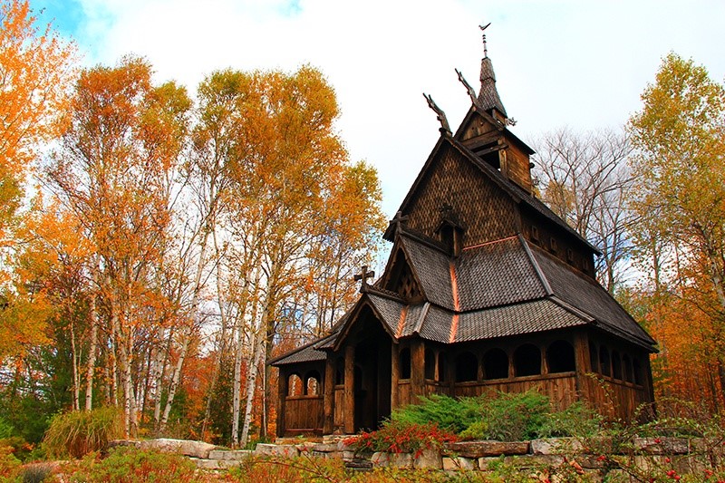 Wooden building in a clearing surrounded by trees with fall colors.