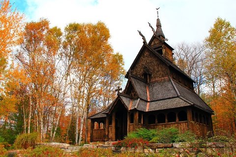 Wooden building in a clearing surrounded by trees with fall colors.