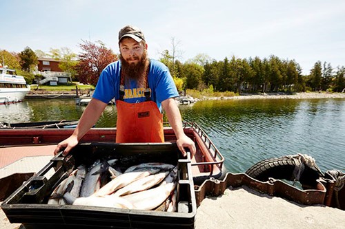 A fisherman stands proudly over his catches of the day.