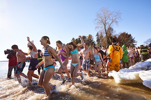 Dozens of people run in swimsuits and costume into Lake Michigan for the Polar Plunge.