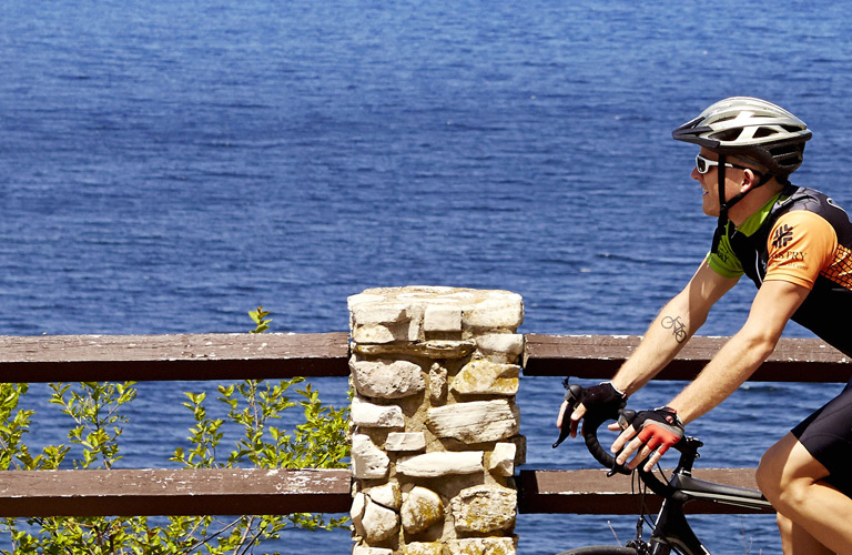 A cyclist riding next to the lake.