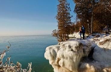 People standing at a snow-covered overlook at the edge of the lake.