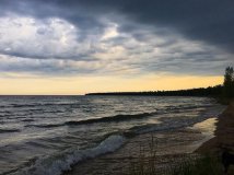 The sun setting over the lake on a cloudy day.