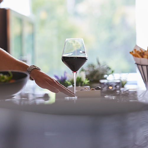 A hand on the foot of a glass of red wine