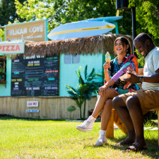 Couple sitting and eating ice cream in front of a food stand.