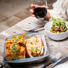 Table with two dinner entrees and a glass of red wine.