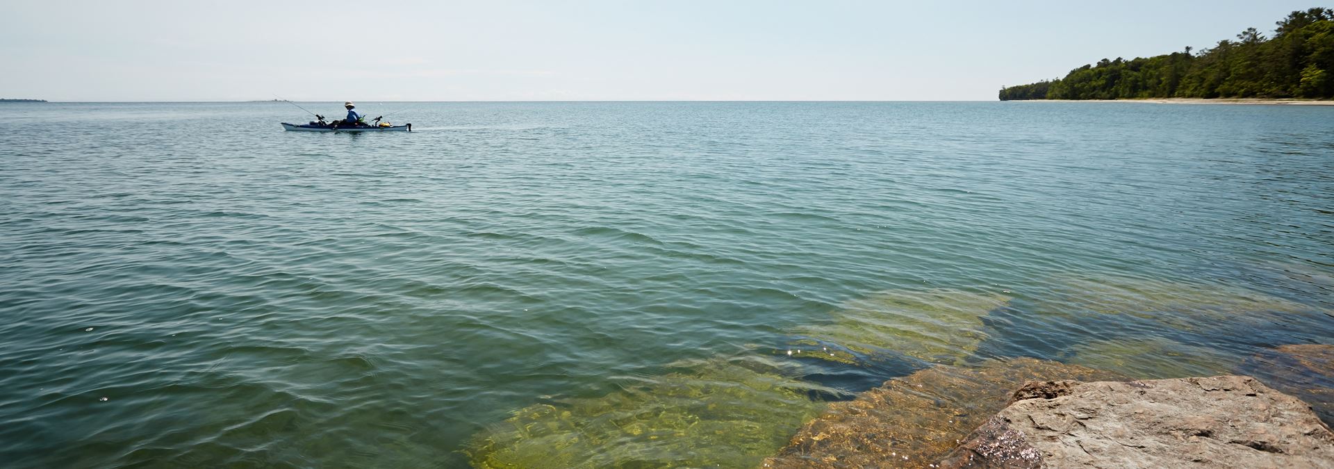 A person on the lake fishing from a kayak.