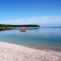 A view of the rock-covered Schoolhouse Beach under an electric blue sky.