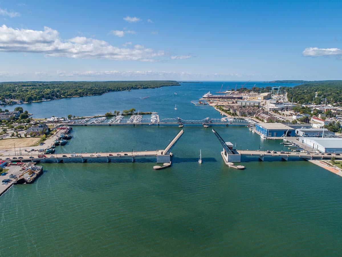 An aerial view of a huge canal with two bridges and Lake Michigan in the distance.