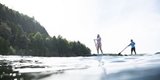 A man and woman on standup paddleboards just off shore