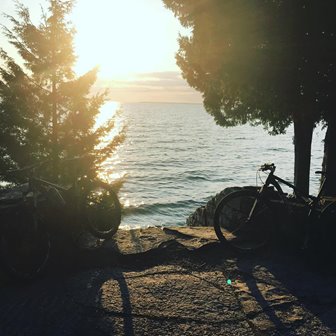 Bicycles parked at the edge of the lake as the sun sets.