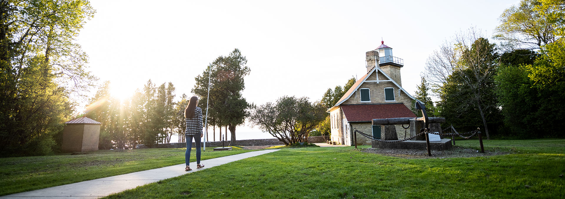 A woman walking toward a building and lighthouse.