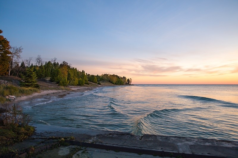 The sun rising over the lakeshore.