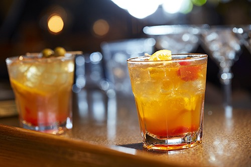 Two old-fashioned sit on a bar.