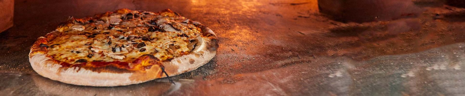 A pizza coming out of a brick oven