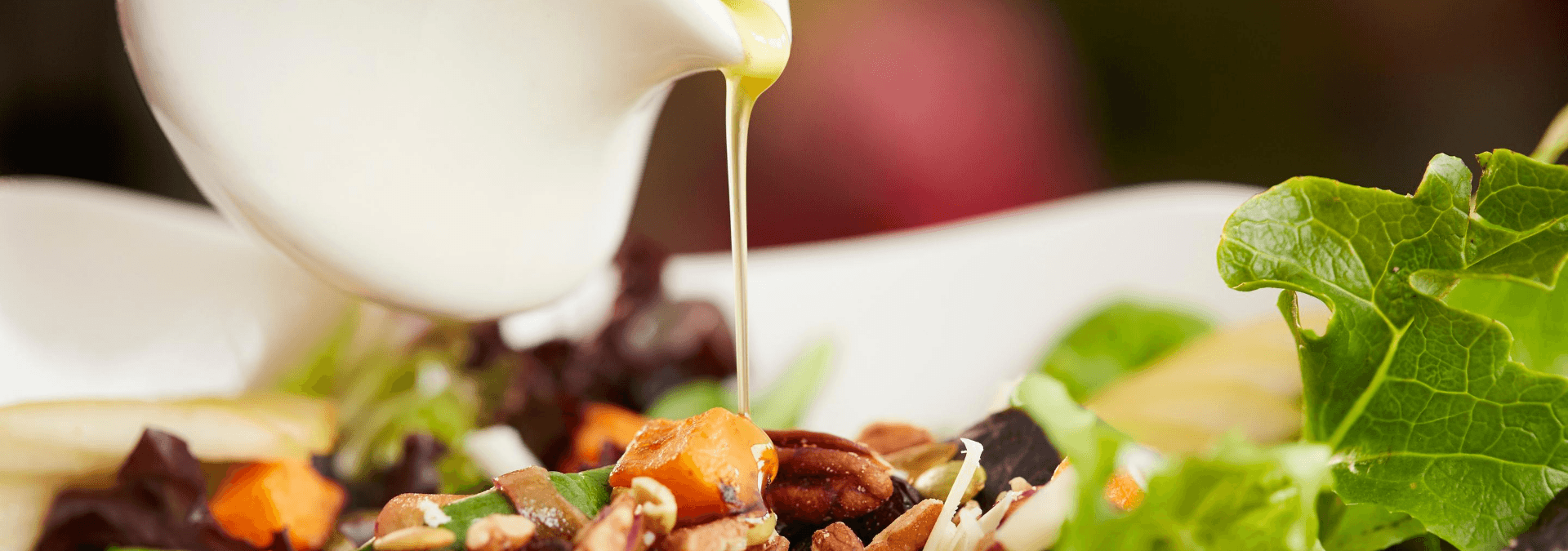 A closeup of dressing being poured over a salad