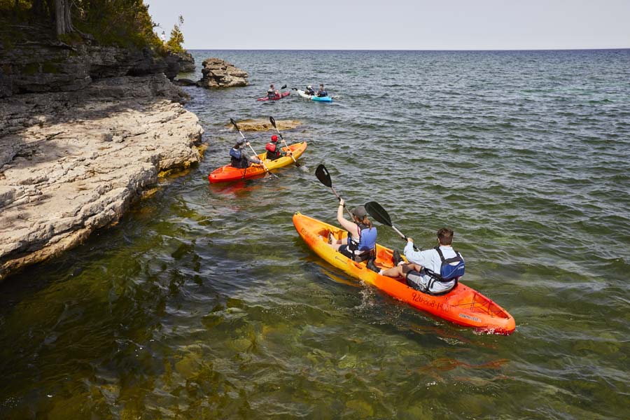 A group kayaks along limestone bluffs and caves.