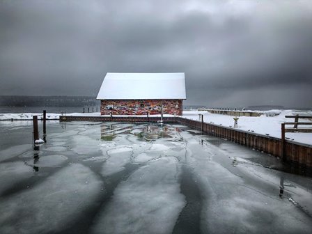 A graffiti-covered building beyond the ice-covered lake.