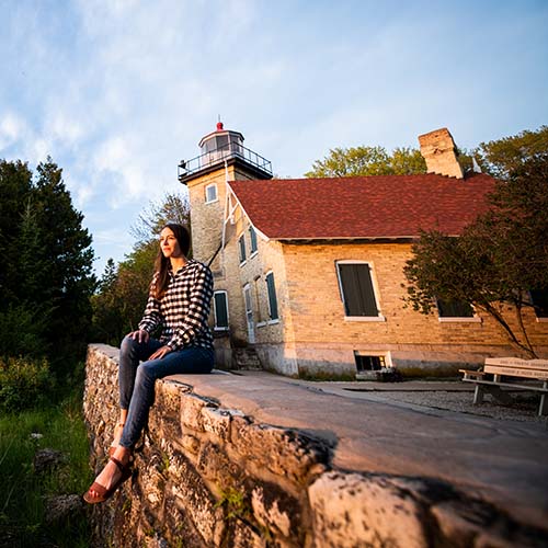 A woman sitting on a wall ledge by a building