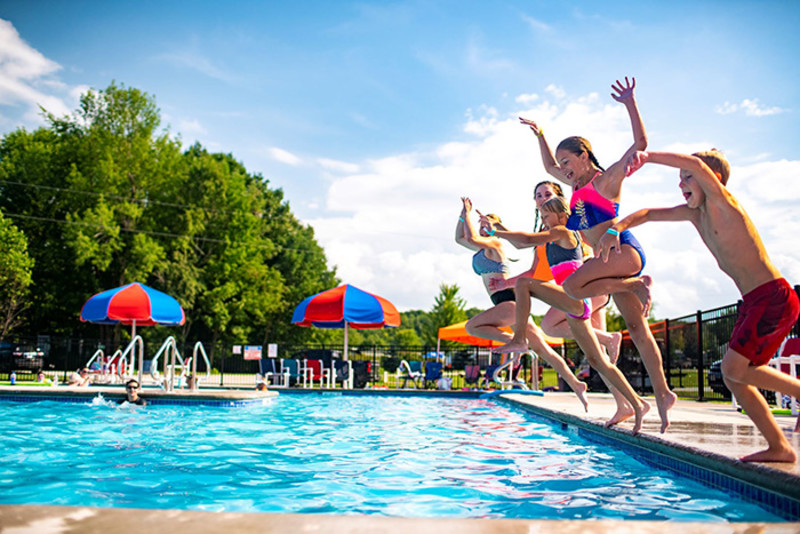 Children jumping into a pool.