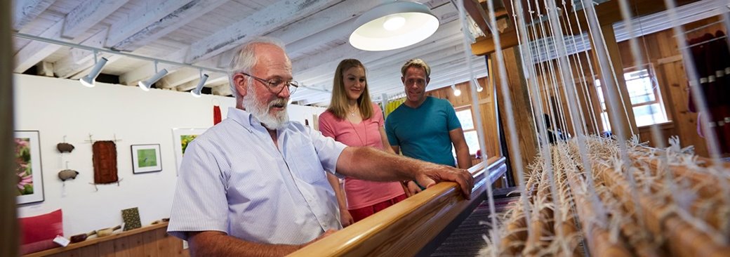 Couple watching a man work with a loom.