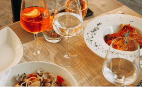 Table with plates of food and wine glasses.