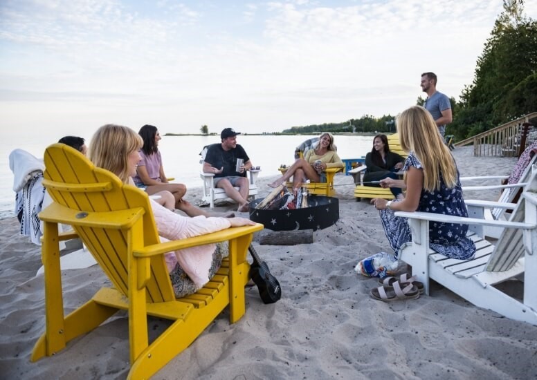 People around a fire pit on the beach.