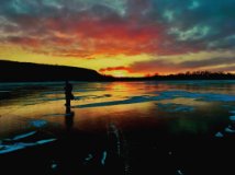 The silhouette of a person standing on the ice at sunset.