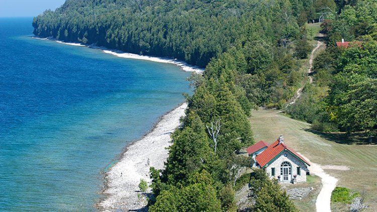 A house on the lake at the edge of the woods.