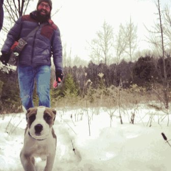 A man walking with a dog through the snow.